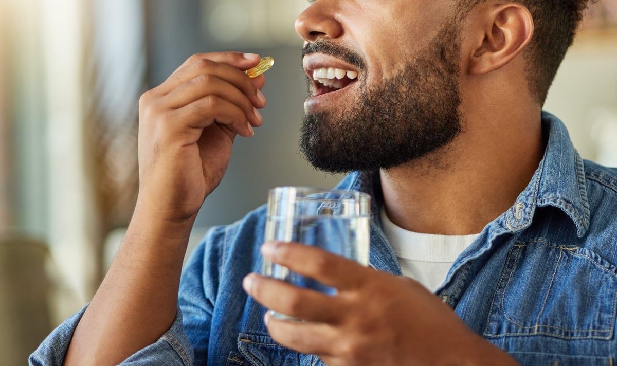 Person taking vitamins and supplements with water supporting hearing health nutrition