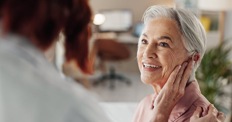 Doctor assisting senior woman with hearing aid consultation