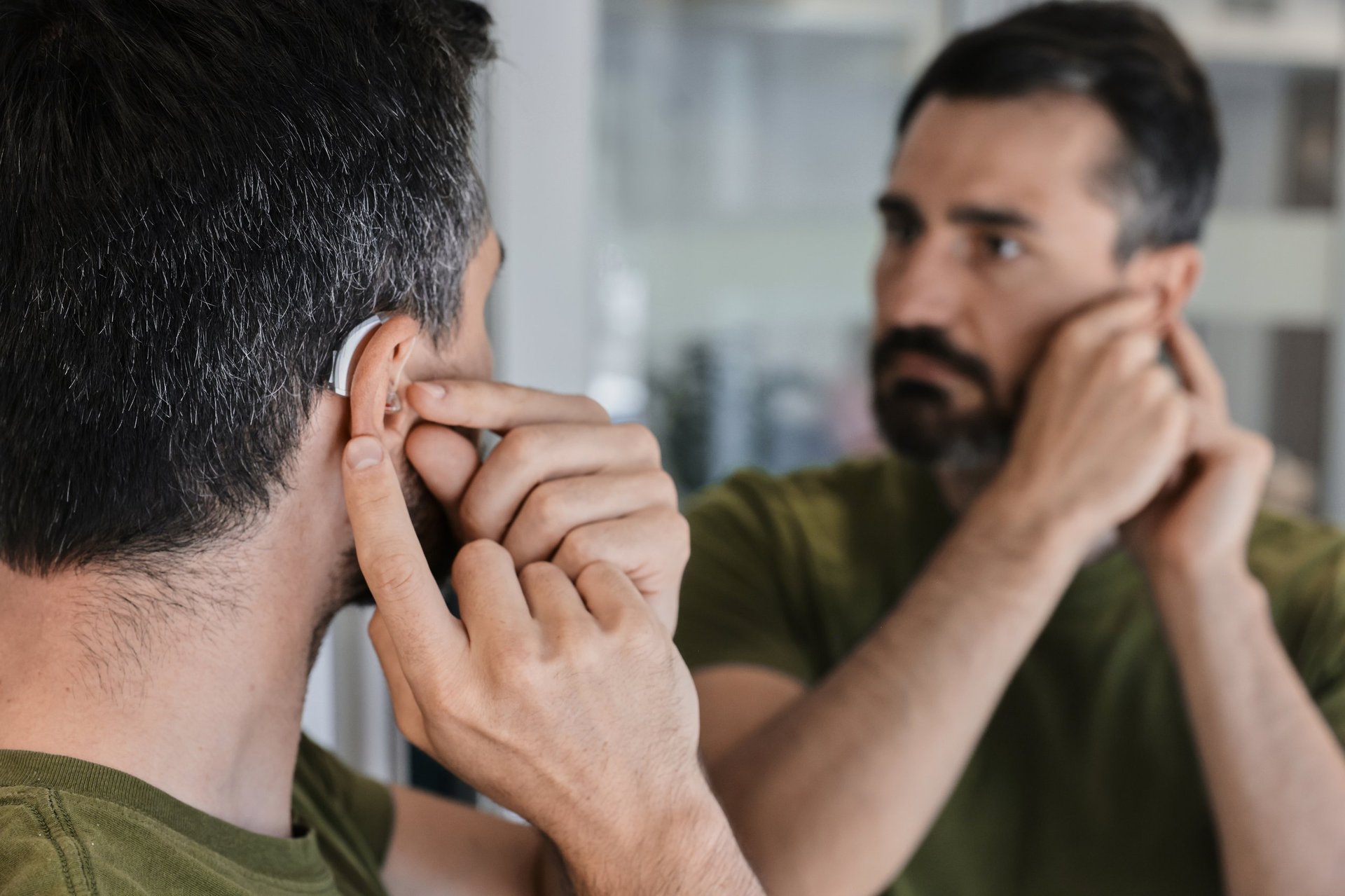 Adult man exploring the comfort and fit of a new behind-the-ear hearing aid