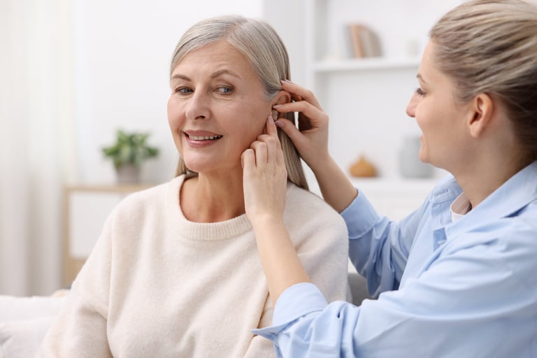 Woman putting hearing aid into her mother's ear at home